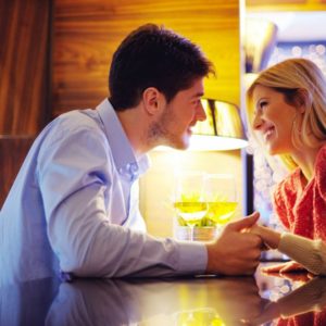 couple holding hands over wine
