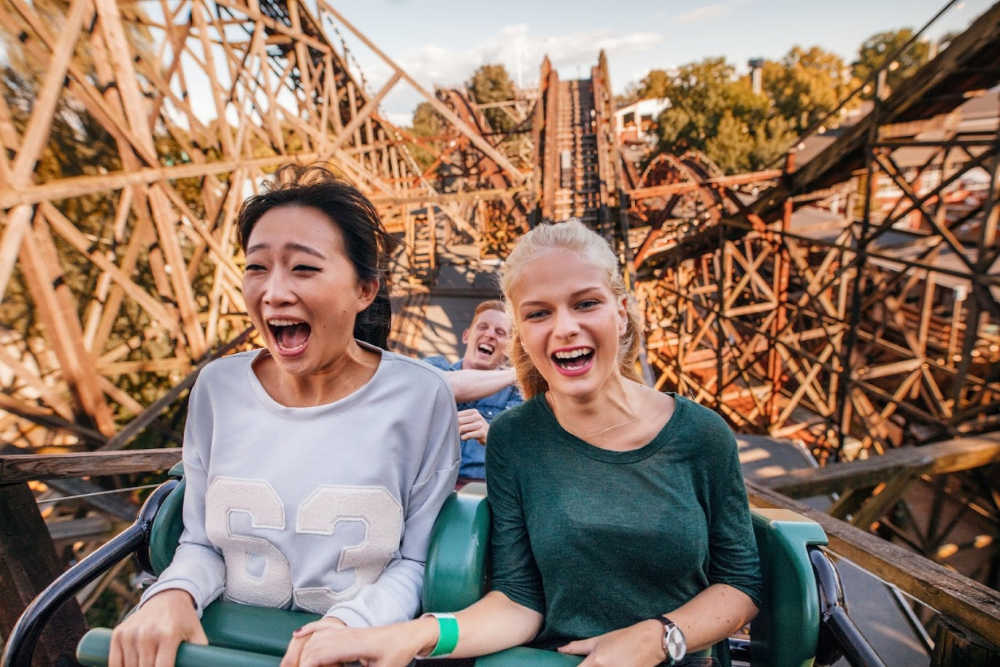 Two young women on a roller coaster with big smiles