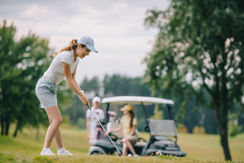 Woman on golf course with two friends in a golf cart