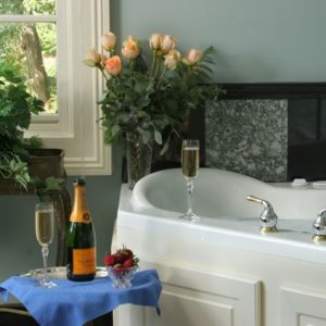 Champagne bottle and two glasses near jacuzzi tub